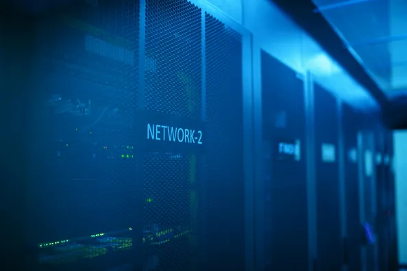 En närbild av serverrum med blå belysning, där en av serverracken är märkt 'NETWORK-2'.